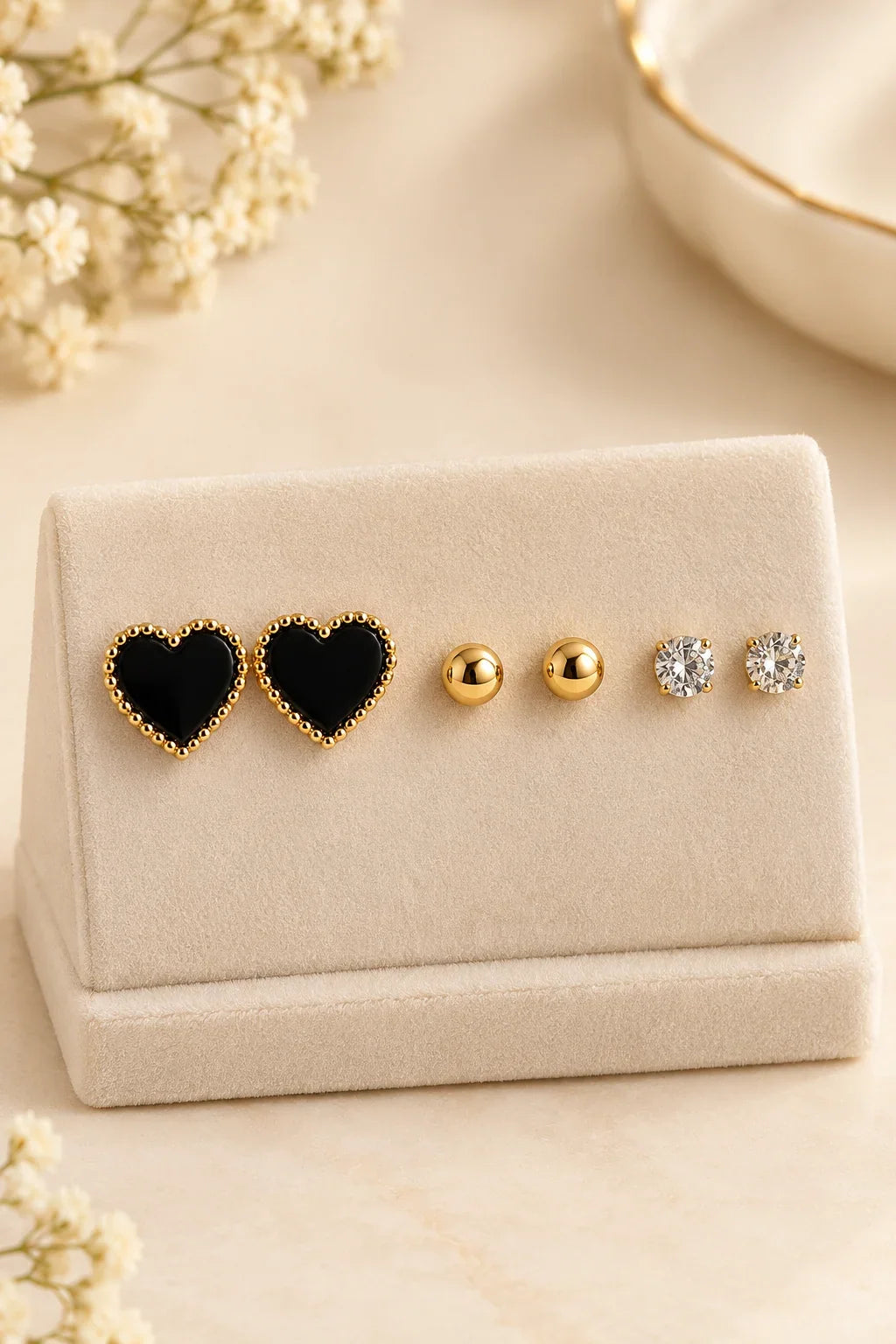 Black heart, gold ball and clear stone stud earrings on a display card