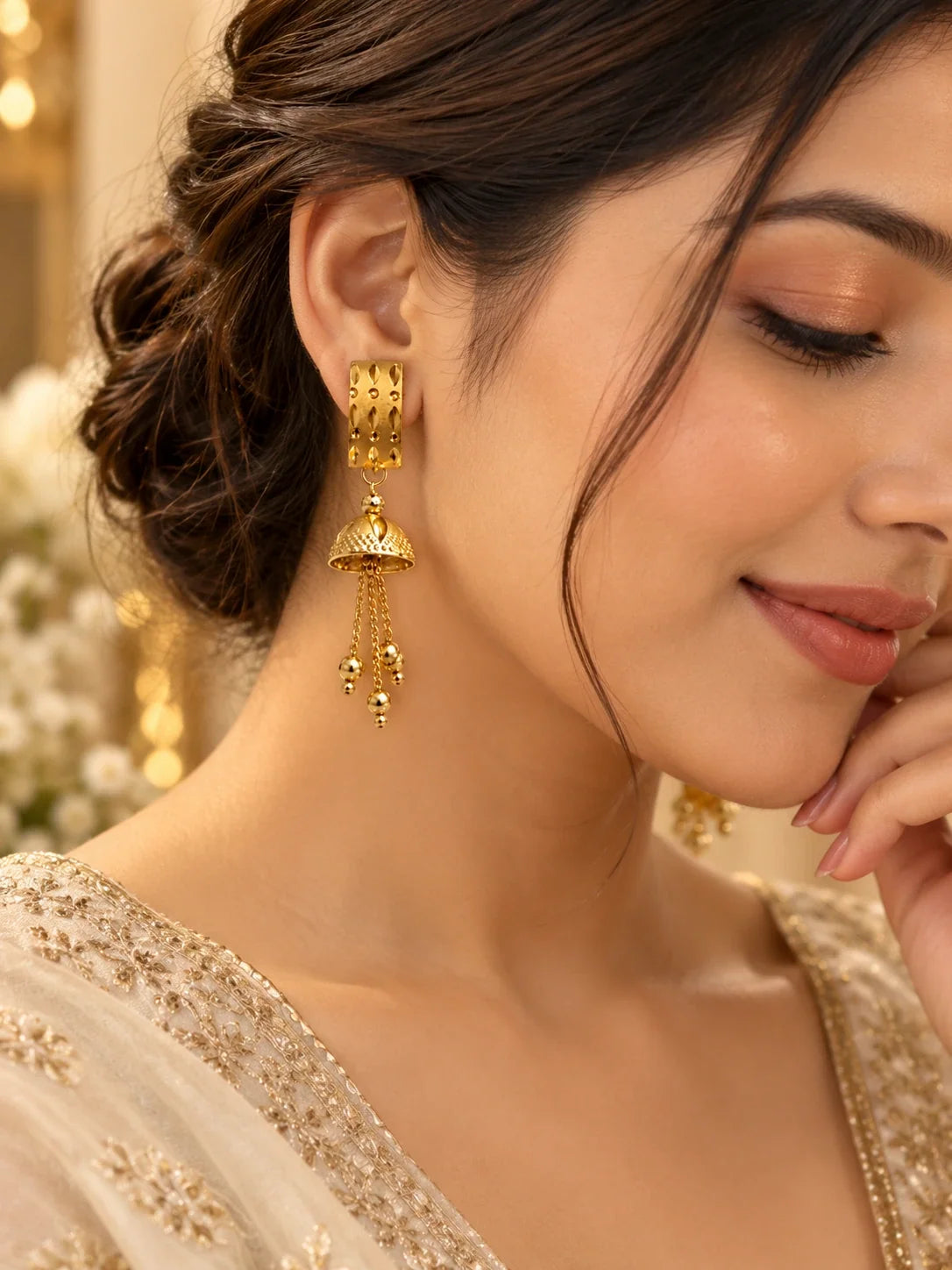 Gold jhumka earrings worn with an ivory outfit