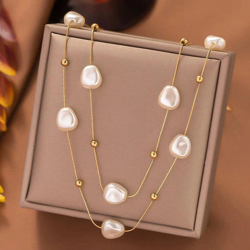 Pearl and gold bead necklace draped over a taupe jewellery box