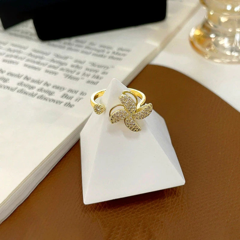 Gold-plated pinwheel ring displayed on a white stand
